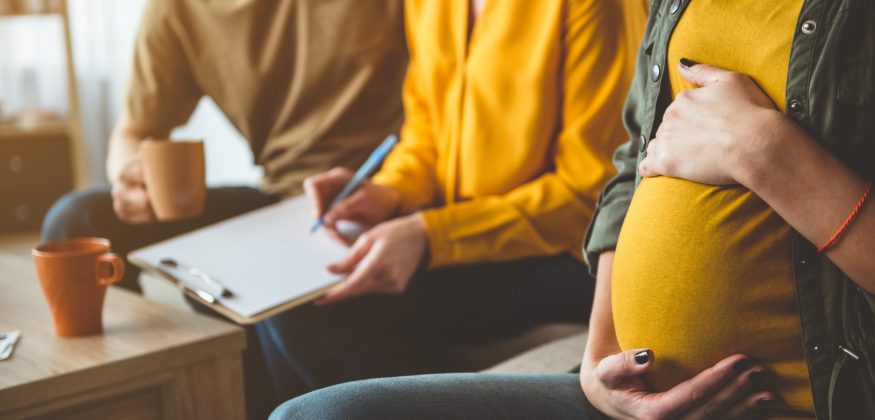 Future parents signing surrogacy agreement with expectant mother