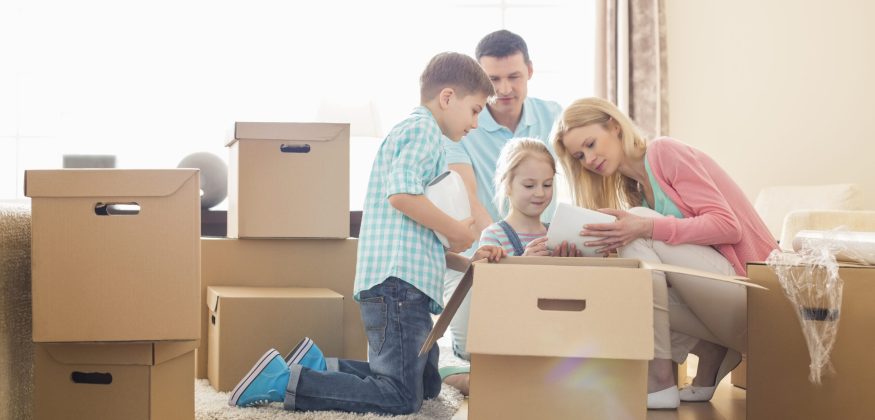 Family unpacking cardboard boxes at new home